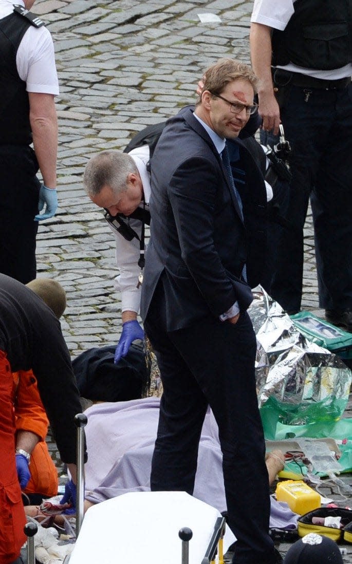 Conservative MP Tobias Ellwood (centre) stands amongst the emergency services at the scene outside the Palace of Westminster, London, after policeman has been stabbed and his apparent attacker shot by officers in a major security incident at the Houses of Parliament