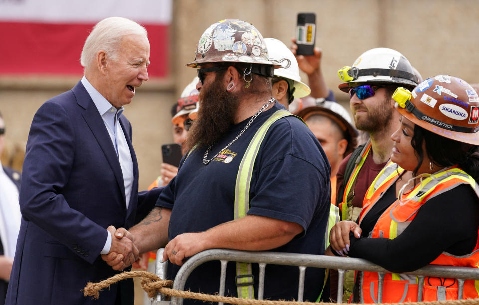 President Biden begroet een arbeider als hij arriveert om te spreken over investeringen in infrastructuurbanen tijdens een bezoek aan Los Angeles, 13 oktober 2022. REUTERS/Kevin Lamarque