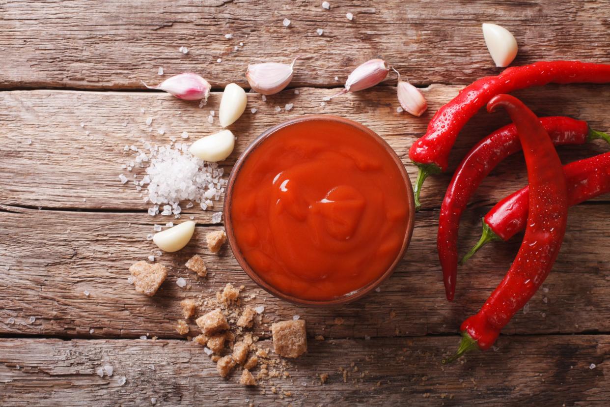 Red chilli sauce Sriracha with ingredients on the table. Horizontal view from above