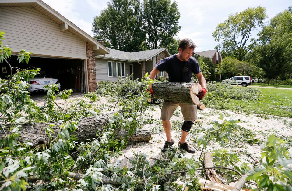 Austin Goodman clears tree debris from his neighbors driveway on Monday, July 31, 2023 after a late night storm downed trees and power lines all over the area.