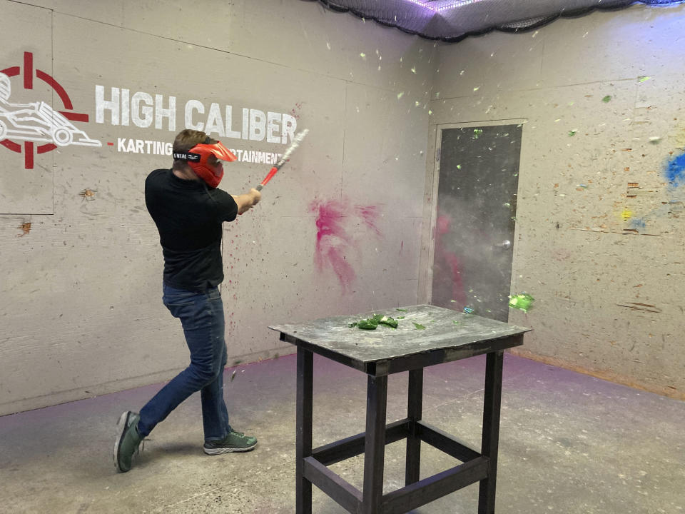 Jordan Munsters, co-founder and president of High Caliber Karting and Entertainment, smashes a glass bottle in one of the venue's "rage rooms," Monday, June 21, 2021, in Meridian Township, Mich. Michigan's coronavirus restrictions will be lifted starting Tuesday, allowing businesses to operate at 100% capacity. (AP Photo/David Eggert)