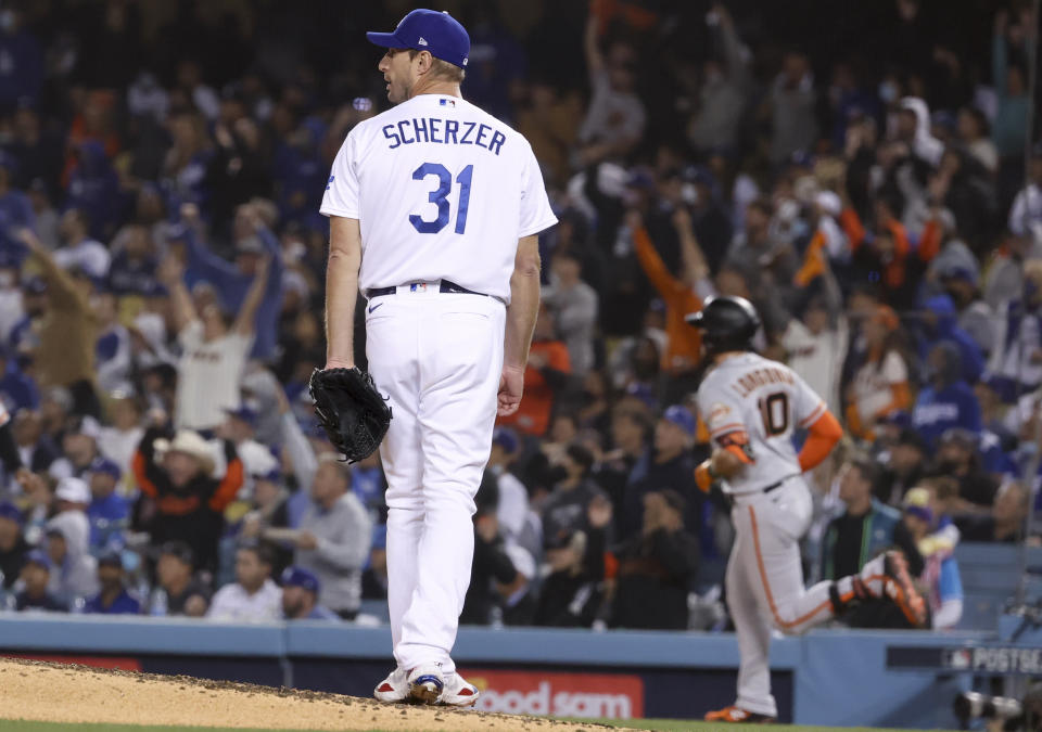 Los Angeles, CA - October 11: Los Angeles Dodgers starting pitcher Max Scherzer, left, looks back after allowing a solo home run to San Francisco Giants' Evan Longoria during the fifth inning in game three of the 2021 National League Division Series at Dodger Stadium on Monday, Oct. 11, 2021 in Los Angeles, CA.(Robert Gauthier / Los Angeles Times via Getty Images)