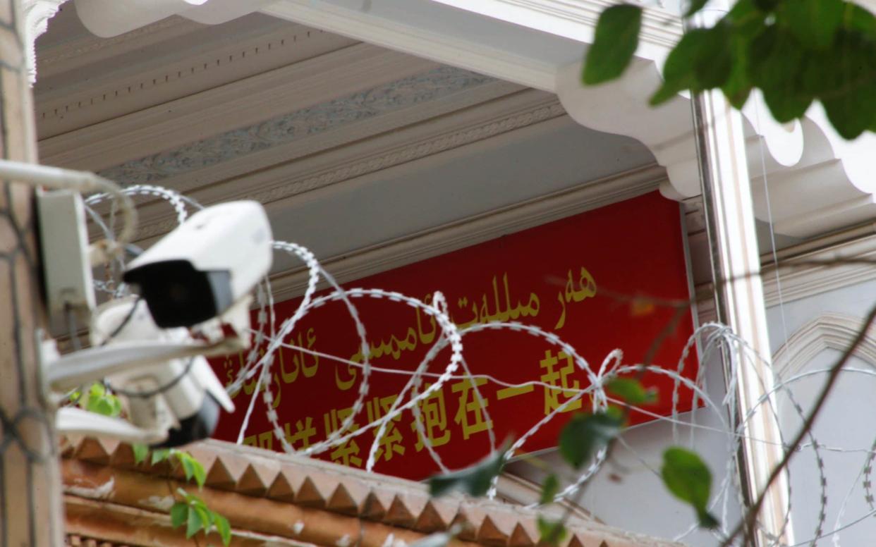 A propaganda banner and a security camera are placed on the walls of a mosque in the Old City in Kashgar - REUTERS