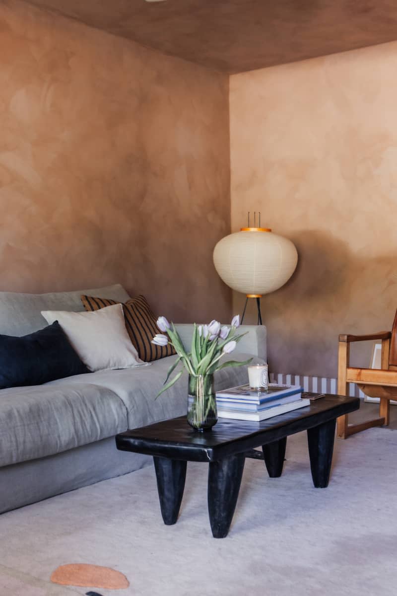 living room with warm textured paint walls, gray sofa, and pale neutral rug/carpet