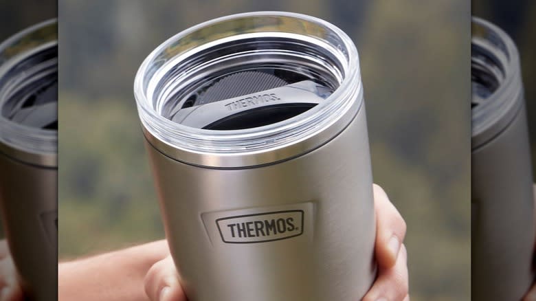 hand holding silver thermos