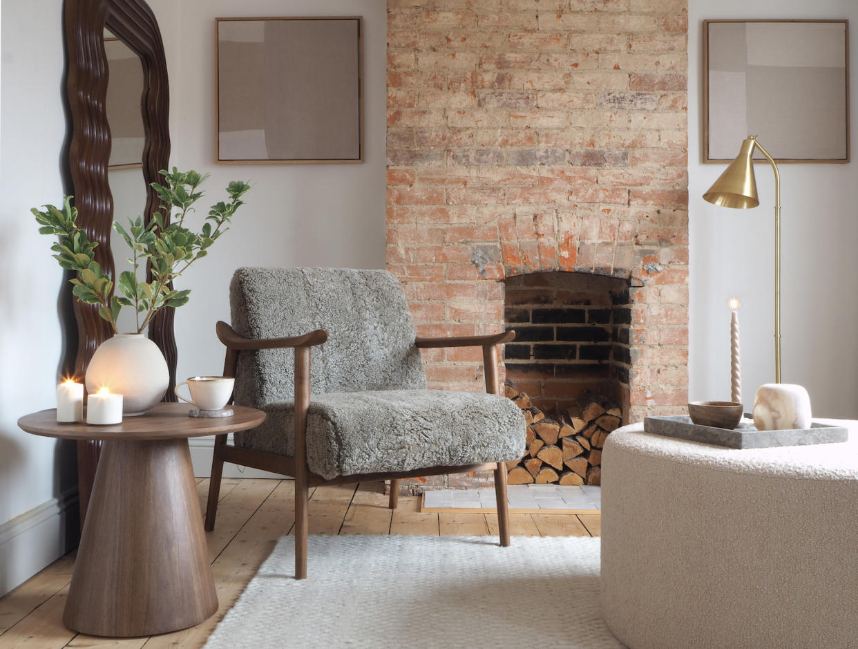  Minimalist living room with a grey boucle chair and brick fireplace. 