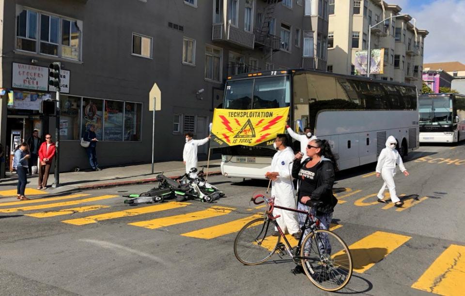 A group of activists blocks commuter tech buses in the Mission District with motorized scooters during a protest in San Francisco.
