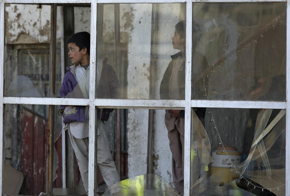 Afghan boys look out from the window of a bakery at the site of a suicide car bomb attack in Kabul