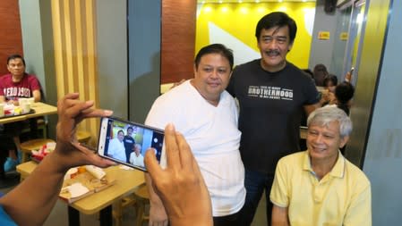 Sonny Parsons, leader of Filipino boyband Hagibis, poses for a photo with fans at a fastfood restaurant in Manila