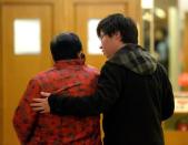 A man consoles an elderly woman as they and other relatives of passengers from the missing Malaysia Airlines flight MH370 leave the lounge after getting no new information in Beijing on March 14, 2014