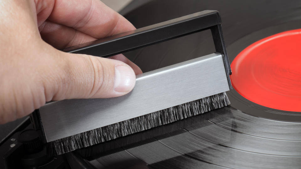 A turntable and cleaning brush, held in a hand 