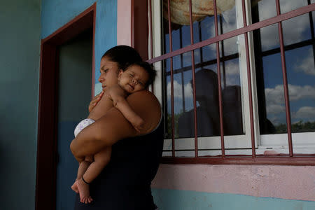 Jennifer Vivas, mother of Eliannys Vivas, who died from diphtheria, carries her baby at the front porch of her home in Pariaguan, Venezuela January 26, 2017. REUTERS/Marco Bello