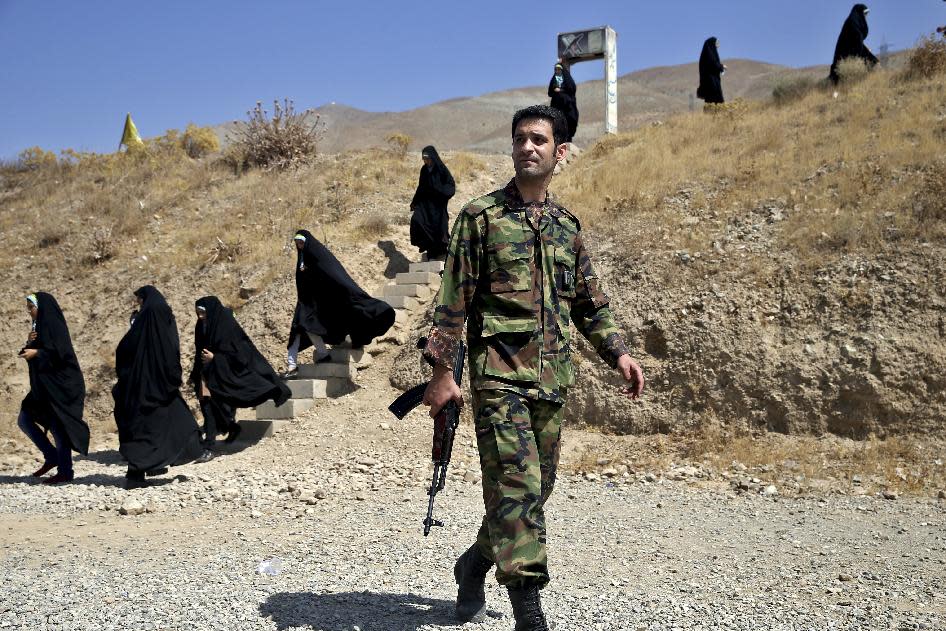 In this Thursday, Aug. 22, 2013 photo, a trainer walks past female members of the Basij paramilitary militia during a training session in Tehran, Iran. With a presence in nearly every city and town across Iran, the paramilitary Basij volunteer corps has an ever-increasing influence on life in the Islamic Republic.(AP Photo/Ebrahim Noroozi)