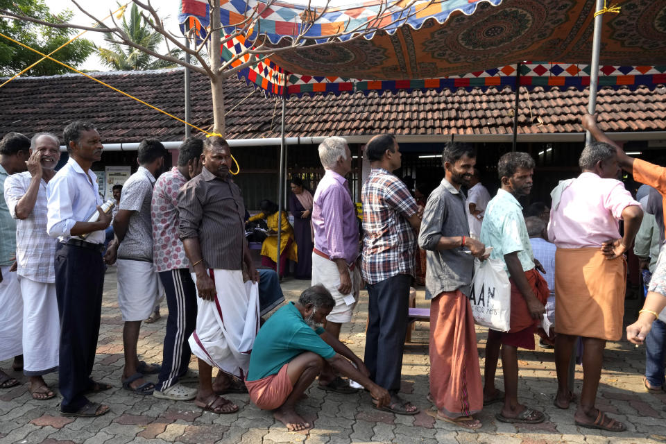 A man squats to rest as he waits with others in a queue to vote during the second round of voting in the six-week-long national election near Palakkad, in Indian southern state of Kerala, Friday, April 26, 2024. (AP Photo/Manish Swarup)