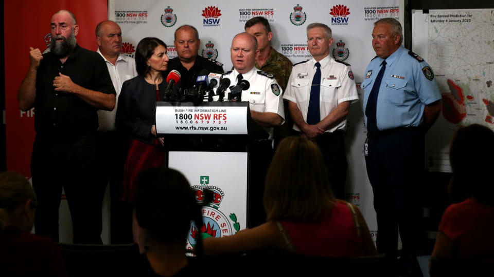 RFS Commissioner Shane Fitzsimmons (middle) speaks to reporters in Sydney providing an update on conditions as NSW and Victoria brace for a day of extreme fire danger.