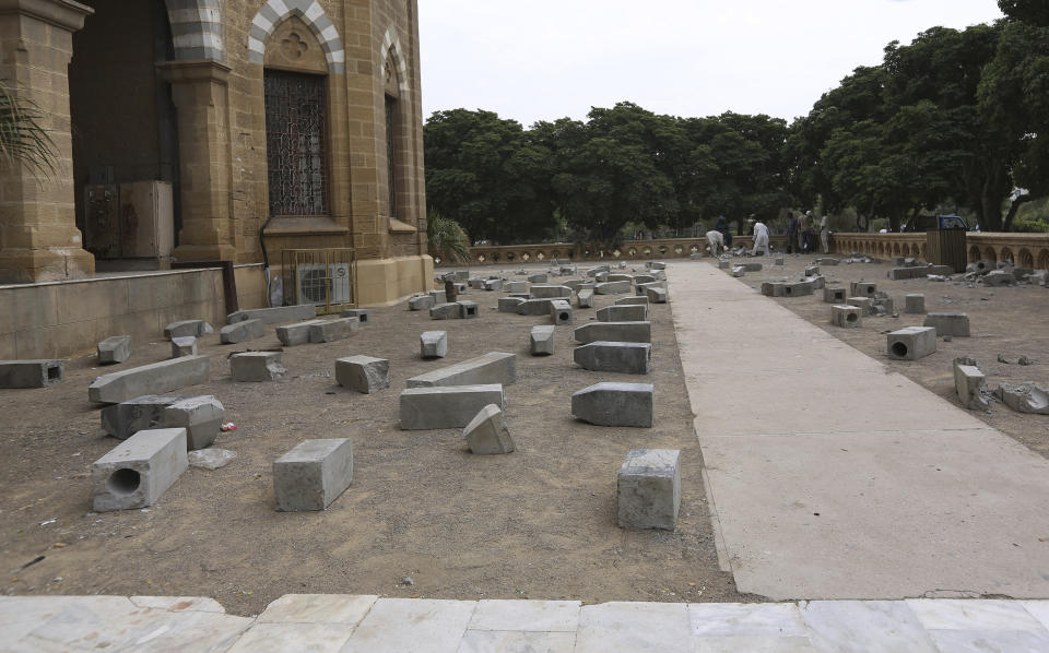 Workers of Karachi Municipal Corporation remove an artwork of concrete tombstones marking the number of "extrajudicial killings", at Frere Hall in Karachi, Pakistan, Tuesday, Oct. 29, 2019. A Pakistani artist says authorities closed her exhibition in Karachi that sought to denounce police raids led by an infamous officer that had killed hundreds of people. (AP Photo/Fareed Khan)