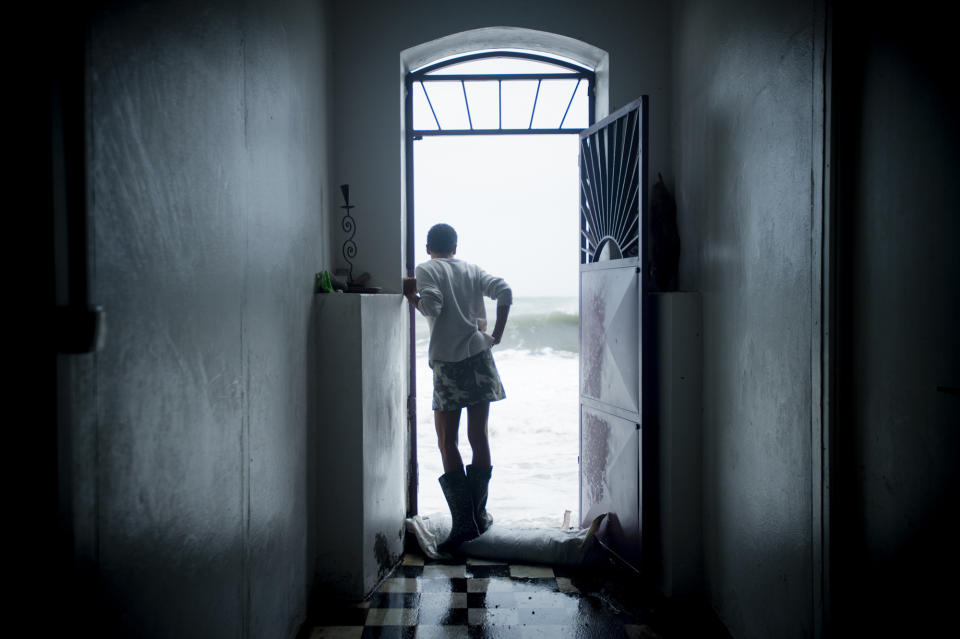 <p>A resident stands at her doorstep as she looks at strong waves in Saint-Pierre, on the French Caribbean island of Martinique, after it was hit by Hurricane Maria, on Sept. 19, 2017. (Photo: Lionel Chamoiseau/AFP/Getty Images) </p>