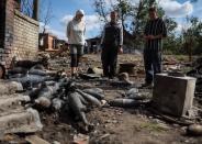 Residentes localescerca de municiones de mortero en una calle destruida en el pueblo de Kamyanka