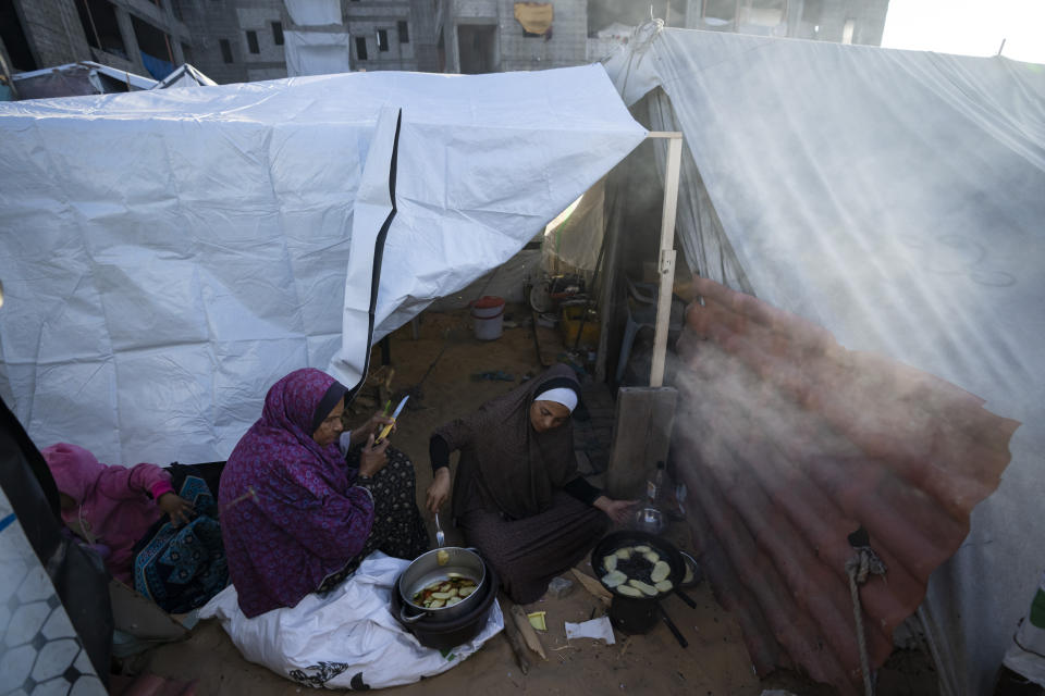 Randa Baker, a la derecha, desplazada por el bombardeo israelí sobre la Franja de Gaza, prepara la comida del iftar con su madre en el primer día de Ramadán, en un campamento improvisado en la zona de Muwasi, en el sur de Gaza, el 11 de marzo de 2024. (AP Foto/Fatima Shbair)