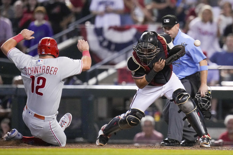 Philadelphia Phillies' Kyle Schwarber is safe at home past Arizona Diamondbacks catcher Gabriel Moreno on a hit by Alec Bohm during the sixth inning in Game 4 of the baseball NL Championship Series in Phoenix, Friday, Oct. 20, 2023. (AP Photo/Ross D. Franklin)