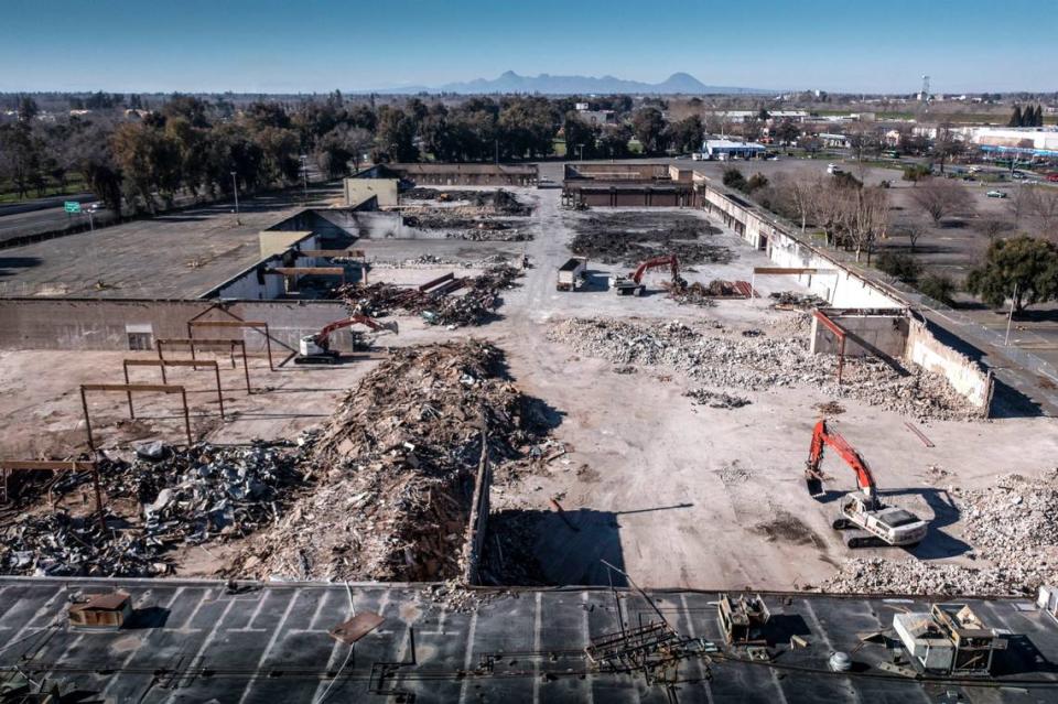 As the Sutter Buttes stand the background, the former Peach Tree Mall in Linda is demolished Thursday. The mall never recovered after flooding after a 1986 levee break.