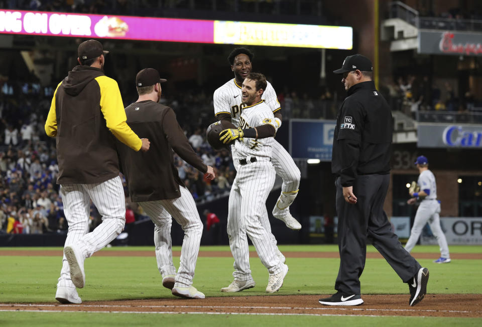 San Diego Padres' Austin Nola, center, is congratulated by Jurickson Profar, background, after Nola drove in the winning run against the Los Angeles Dodgers in the 10th inning of a baseball game Saturday, April 23, 2022, in San Diego. (AP Photo/Derrick Tuskan)