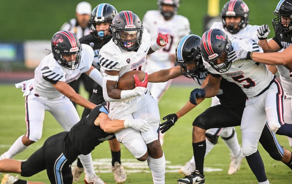 San Joaquin Memorial’s Jordan Colbert, center, plows his way upfield for a gain during their game against Clovis North at Veterans Memorial Stadium in Clovis on Friday, Aug. 18, 2023.