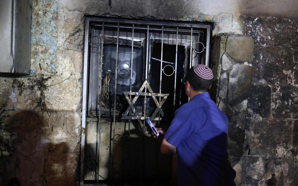 An Israeli man looks inside a synagogue, after it was set on fire by Arab-Israelis, in the mixed Jewish-Arab city of Lod - AFP