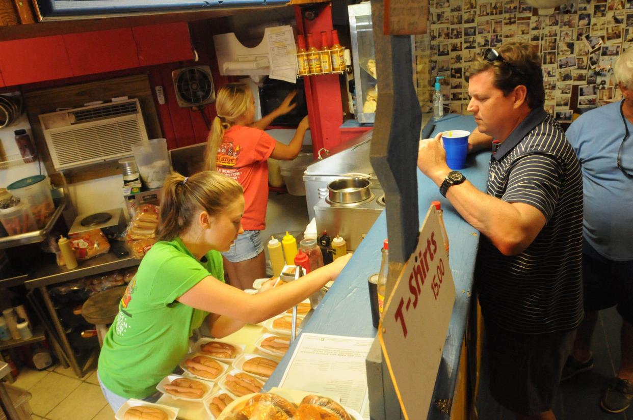 Madi Stoudenmire and Nicole Leitz make a batch of hot dogs for Mike Raines of Charlotte, N.C. at The Trolly Stop that was started in 1976 in Wrighstville Beach, N.C. KEN BLEVINS/STARNEWS
