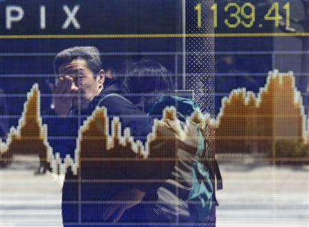 A man is reflected on a screen displaying a graph showing movements of the Tokyo Stock Exchange Stock Price Index (TOPIX), outside a brokerage in Tokyo April 14, 2014. REUTERS/Issei Kato