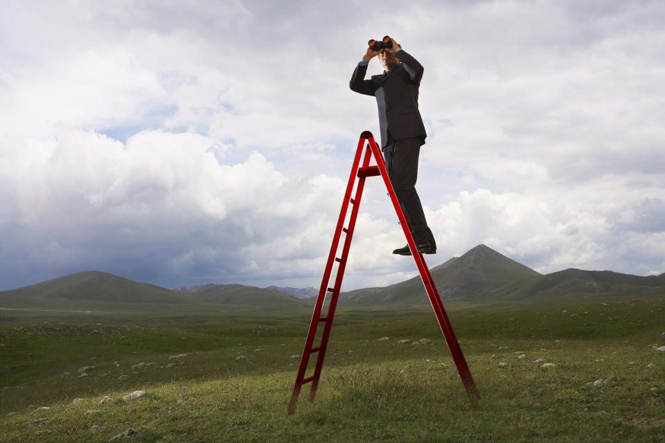 Guy in a suit on a ladder with binoculars.