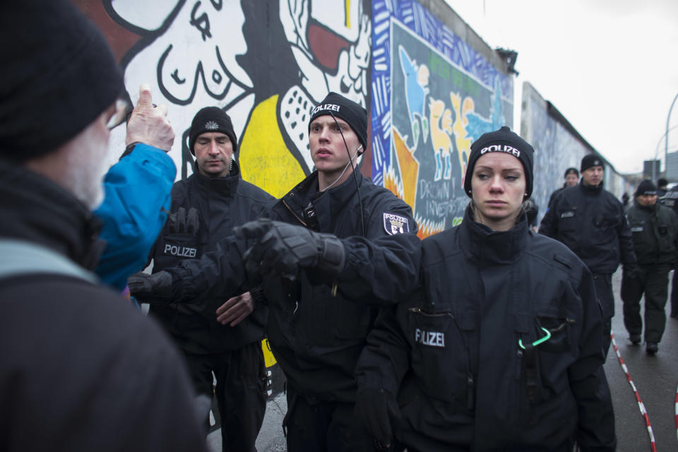 A German police officers reacts to protestors as they protect a part of the former Berlin Wall in Berlin, Germany, Friday, March 1, 2013. Construction crews stopped work Friday on removing a small section from one of the few remaining stretches of the Berlin Wall to make way for a condo project after hundreds of protesters blocked their path.(AP Photo/Markus Schreiber/Pool)