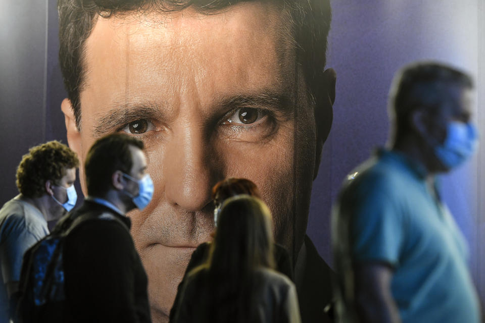 People wearing masks for protection against COVID-19 are backdropped by a large poster of Nicusor Dan, candidate for mayor in Bucharest, Romania, Sunday, Sept. 27, 2020. Exit polls place Nicusor Dan, the mayor candidate backed by the USR-PLUS Alliance and the ruling Liberal Party, ahead of the incumbent mayor of the Romanian capital, Gabriela Firea, backed by the Social Democratic Party in local elections. (AP Photo/Andreea Alexandru)