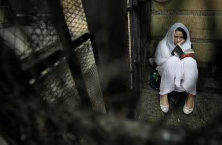Aya Hijazi, founder of Belady, an NGO that promotes a better life for street children, sits reading a book inside a holding cell as she faces trial on charges of human trafficking at a courthouse in Cairo, Egypt March 23, 2017. Picture taken March 23, 2017. REUTERS/Mohamed Abd El Ghany