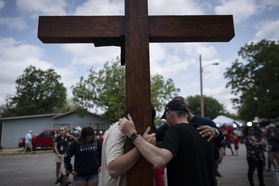 Dan Beazley, right, with his son Joey Beazley, from Detroit, carry their wooden cross as they pray at a memorial outside Robb Elementary School in Uvalde, Texas, Monday, May 30, 2022. Multiple people were killed by an 18-year-old gunman at the school last week. (AP Photo/Wong Maye-E)