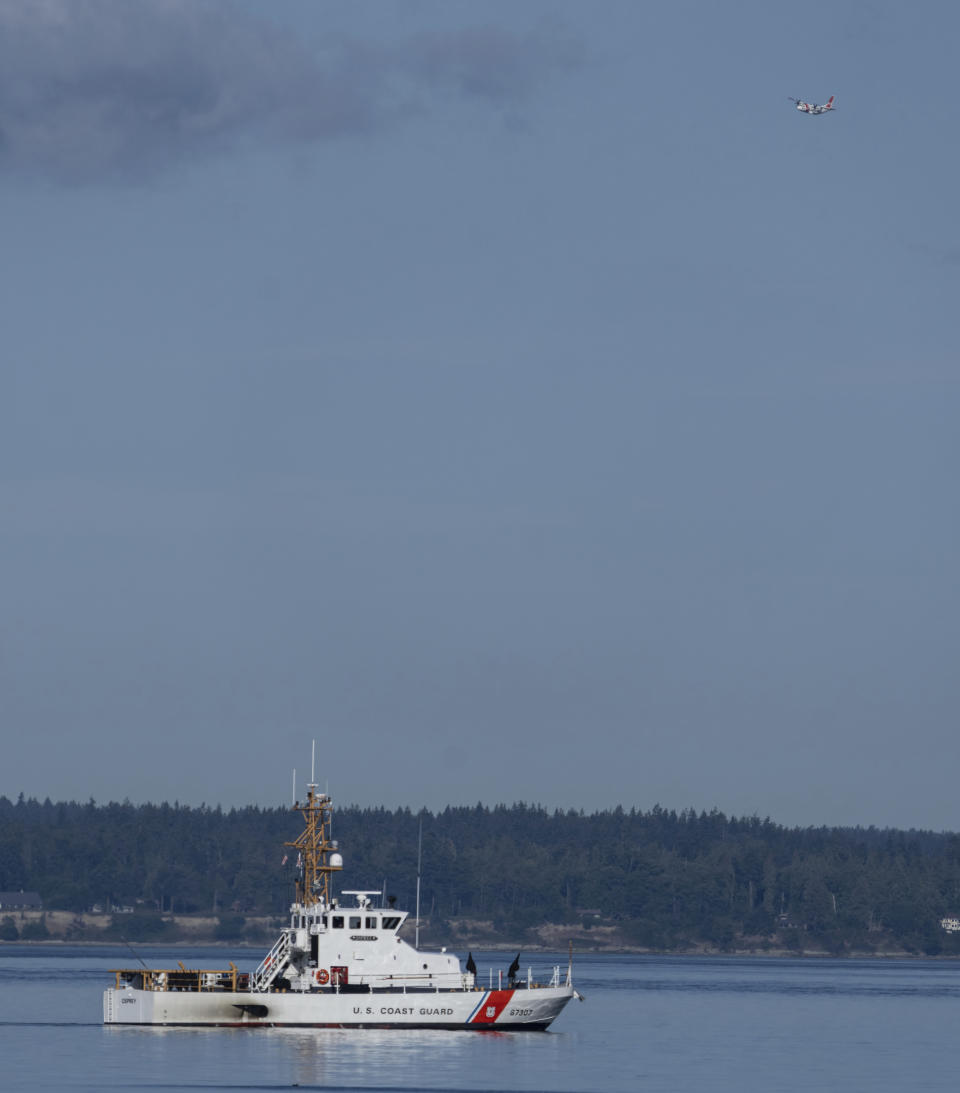 U.S. Coast Guard boat and plane search the area, Monday, Sept. 5, 2022, near Freeland, Wash., on Whidbey Island north of Seattle where a chartered floatplane crashed the day before. The plane was en route from Friday Harbor, Wash., to Renton, Wash. (AP Photo/Stephen Brashear)