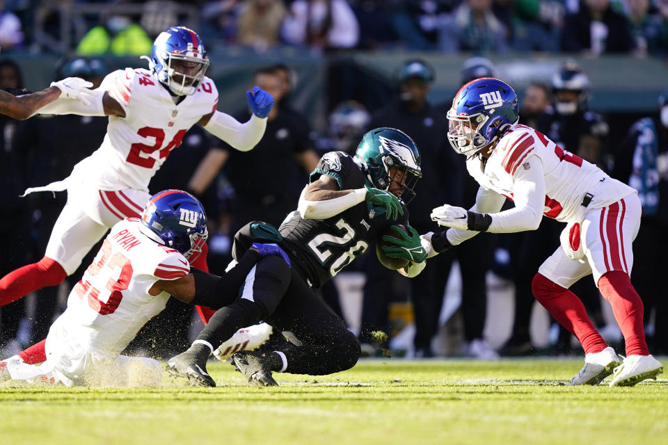 Philadelphia Eagles' Miles Sanders, center, is tackled by New York Giants' Logan Ryan, left, an Xavier McKinney during the first half of an NFL football game, Sunday, Dec. 26, 2021, in Philadelphia. (AP Photo/Matt Rourke)