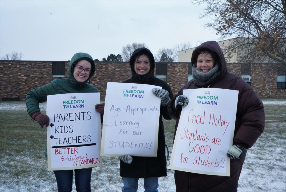 Teachers Whitney Rederth, Kelly Steckler, Crystal Groeneweg, hold signs bringing awareness about the proposed K-12 social studies standards at Legacy Elementary School in Tea on Wednesday, Nov. 16, 2022.