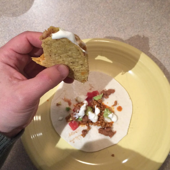 The contents of a taco spilling onto another tortilla