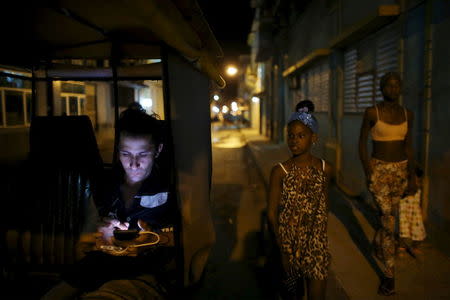 Self-employed pedicab driver Danilo Guerra, 25, uses his mobile phone as he waits for clients in downtown Havana April 12, 2016. REUTERS/Alexandre Meneghini