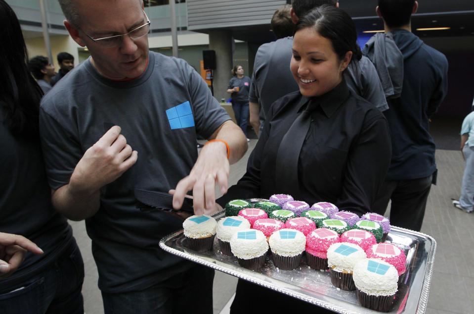 A Microsoft employee reaches for cupcakes being served with the company's logo atop during an event unveiling a new Microsoft Windows operating system Thursday, Oct. 25, 2012, at the company's headquarters in Redmond, Wash. Windows 8, attempts to bridge the gap between personal computers and fast-growing tablets with its touch-enabled interface. It is the most dramatic overhaul of the personal computer market's dominant operating system in 17 years. (AP Photo/Elaine Thompson)