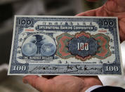 Dr. Robert Schwartz holds a Chinese hundred dollar bill from 1905, issued by the International Banking Corporation, which was affiliated with Citigroup.