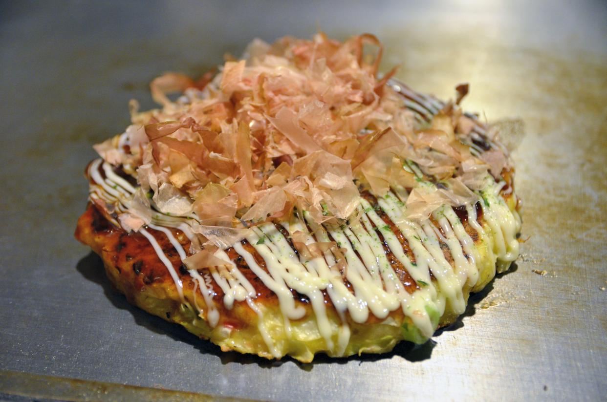 an oyster Okonomiyaki pancake on a grill