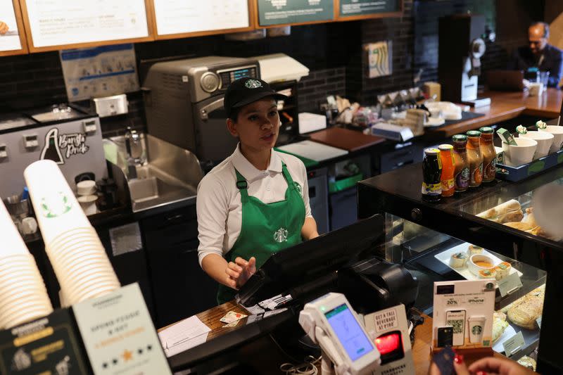 An employee takes a customer's order at a Starbucks' outlet at a market in New Delhi