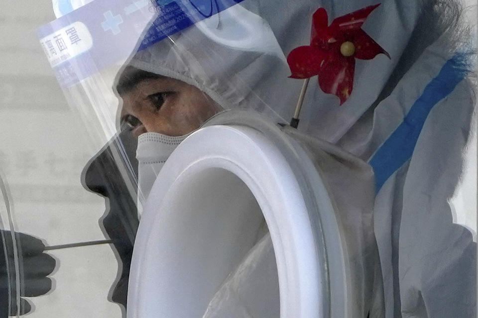 FILE - A worker in protective gear collects a sample from a resident at a coronavirus testing site in Beijing, Nov. 29, 2022. China's sudden reopening after two years holding to a "zero-COVID" strategy left older people vulnerable and hospitals and pharmacies unprepared during the season when the virus spreads most easily, leading to many avoidable deaths, The Associated Press has found. (AP Photo/Andy Wong, File)