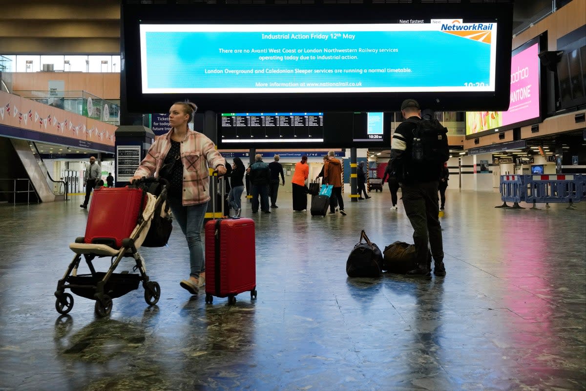 Travellers wait at Euston station in London (AP)