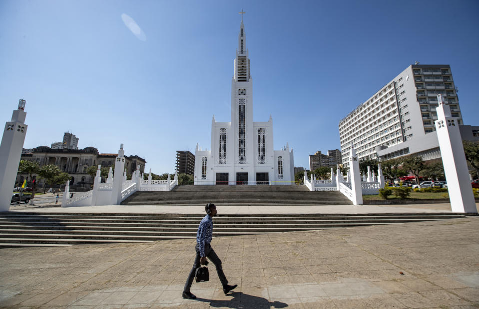A man listens to headphones as he walks past the cathedral, which Pope Francis will visit later this week, in the capital Maputo, Mozambique Tuesday, Sept. 3, 2019. Pope Francis heads this week to the southern African nations of Mozambique, Madagascar and Mauritius, visiting some of the world's poorest countries in a region hard hit by some of his biggest concerns: conflict, corruption and climate change. (AP Photo/Ben Curtis)