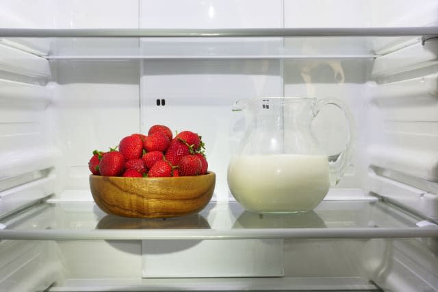 Strawberries  and a pitcher of milk  in the refrigerator.