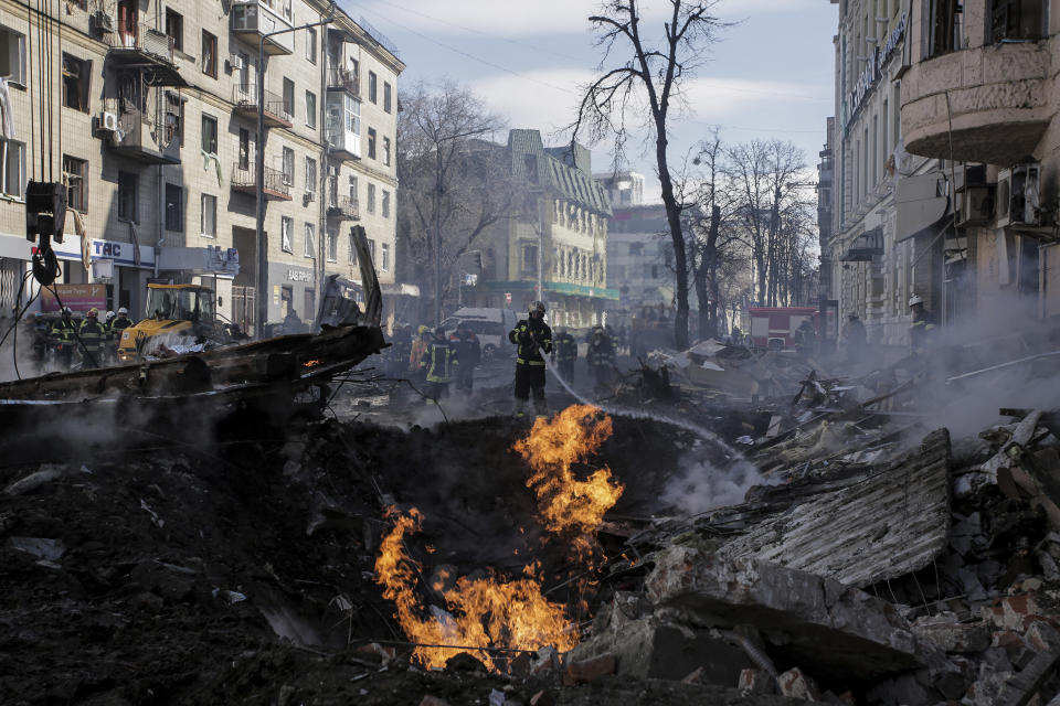 FILE - Firefighters extinguish flames outside an apartment house after a Russian rocket attack in Kharkiv, Ukraine's second-largest city, Ukraine, Monday, March 14, 2022. War has been a catastrophe for Ukraine and a crisis for the globe. One year on, thousands of civilians are dead, and countless buildings have been destroyed. Hundreds of thousands of troops have been killed or wounded on each side. Beyond Ukraine’s borders, the invasion shattered European security, redrew nations’ relations with one another and frayed a tightly woven global economy. (AP Photo/Pavel Dorogoy, File)