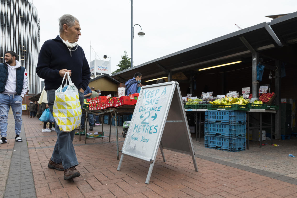 A man holding a shopping bag passes a Covid-19 social distancing sign as he browses fresh fruit and vegetables at the outdoor market on 4th September, 2021 in Leeds, United Kingdom. A combination of Brexit and Covid-19 is reportedly exacerbating an already severe staff shortage in the British food industry, with a lack of fruit and vegetable pickers that could see a hike in food prices across the country. (photo by Daniel Harvey Gonzalez/In Pictures via Getty Images)